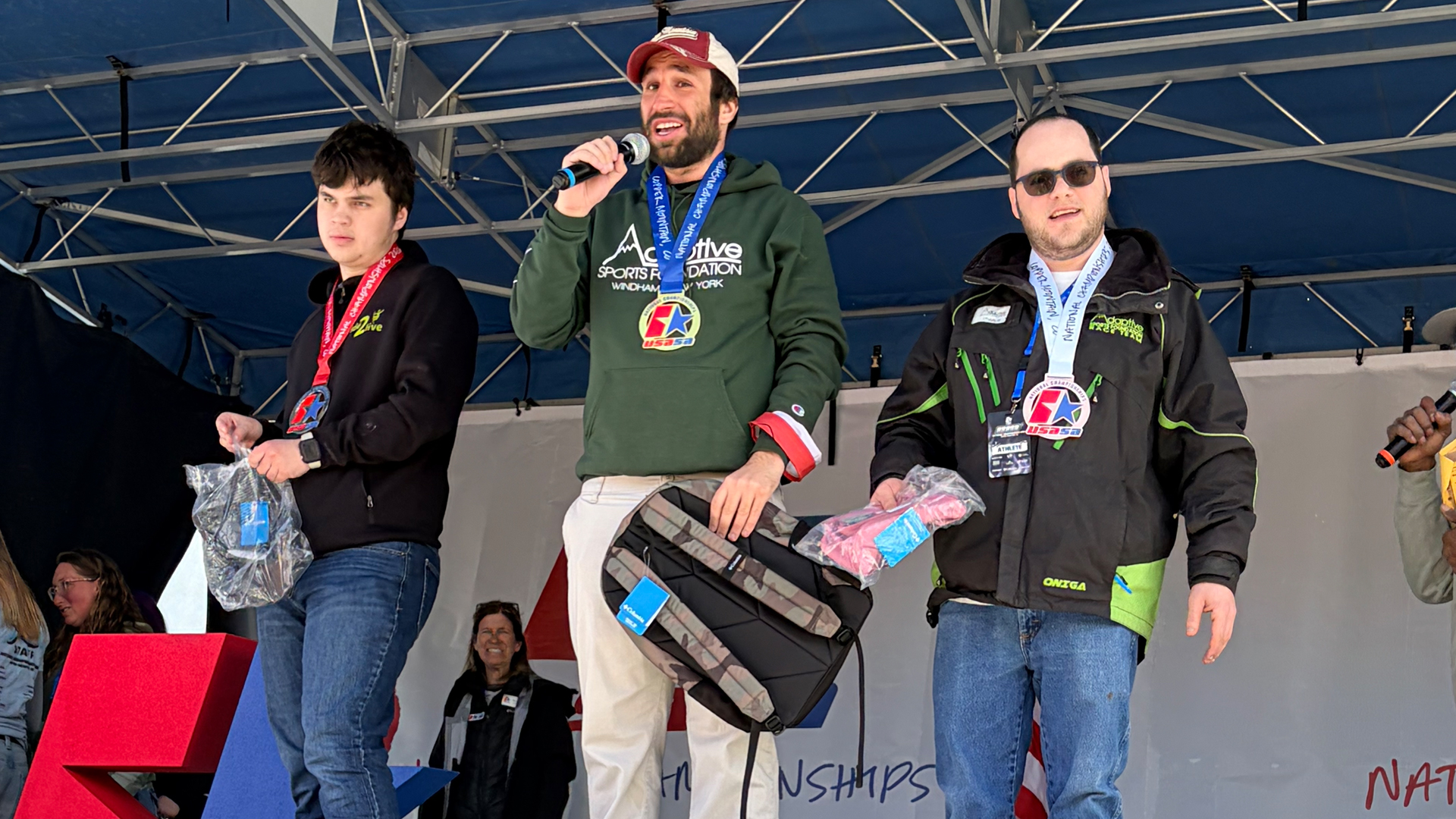 Three men stand on a podium with medals around their necks