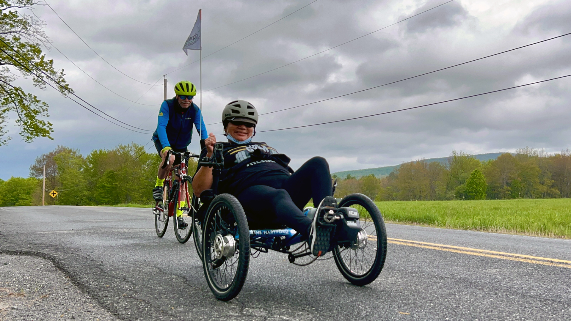 Woman in recumbent bike waves for photo