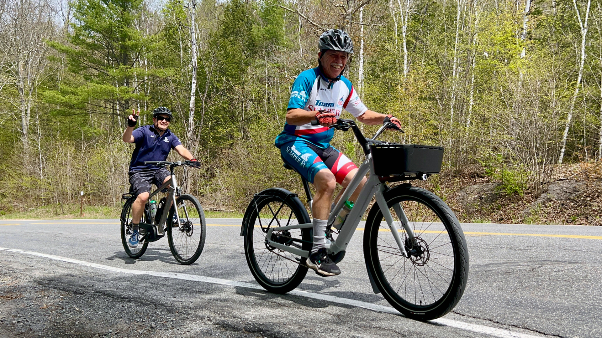 Two men cycling and smiling.