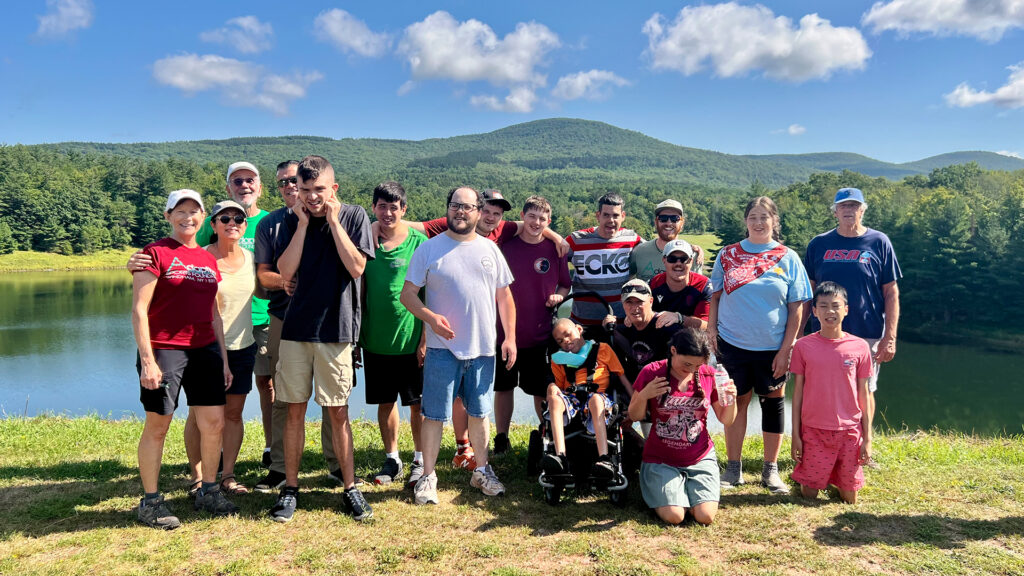 A group of people standing in front of a lake and a mountain