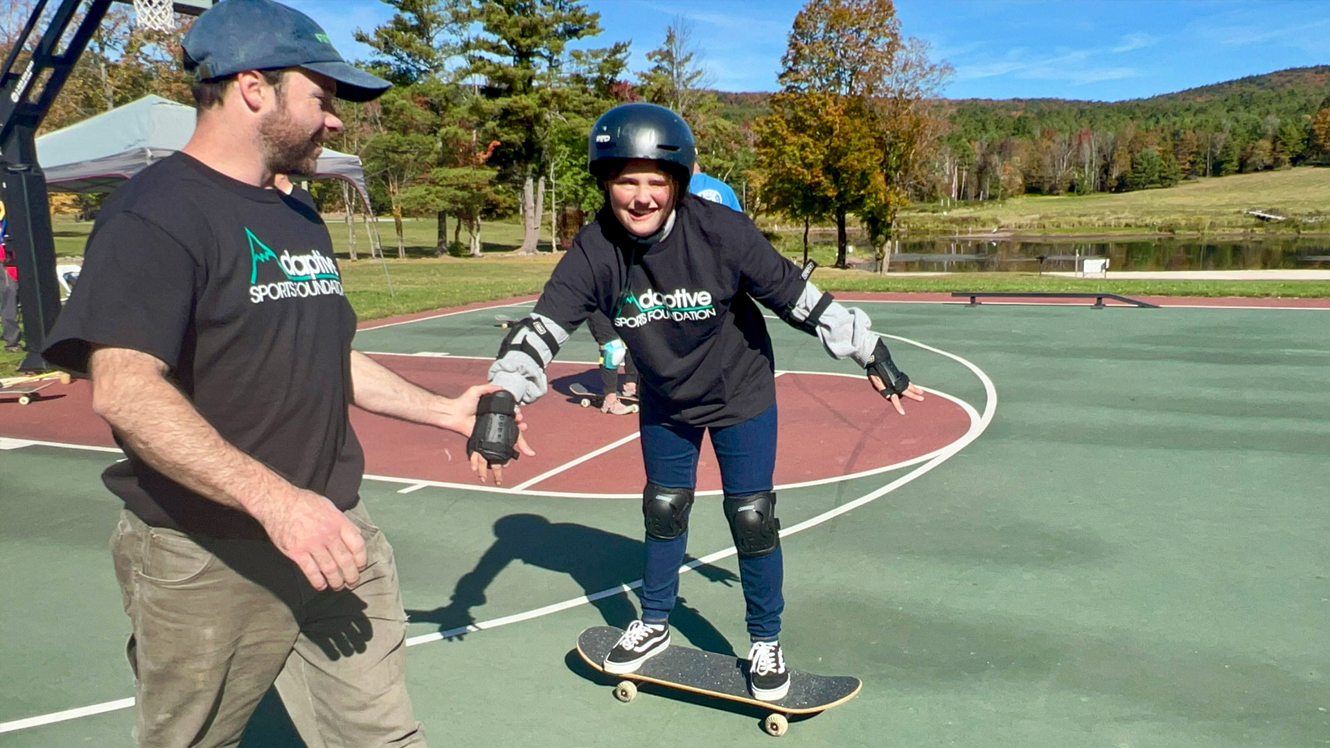 Girl skateboarding while holding coach's hand