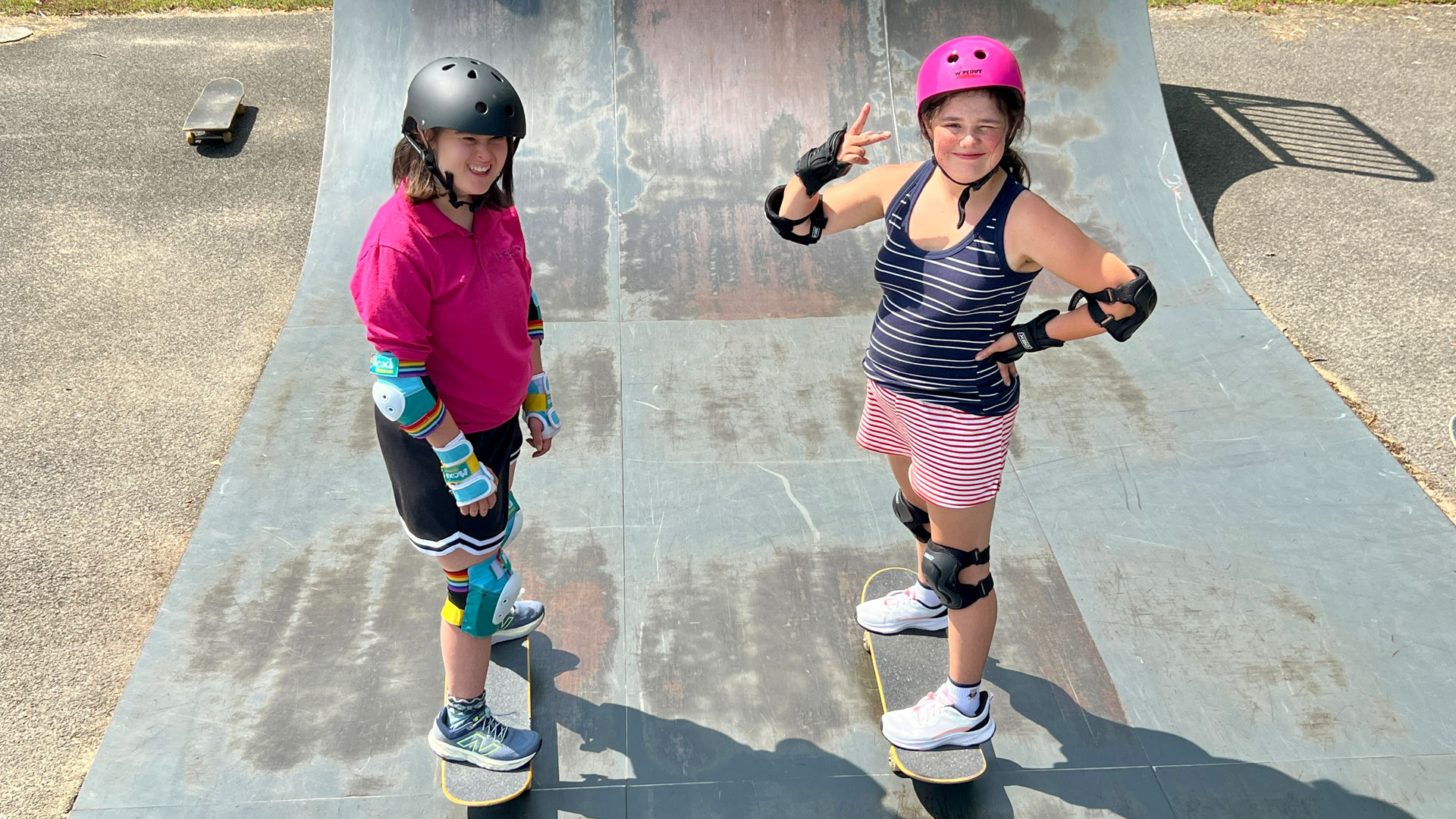 Two Girls on skateboards smiling