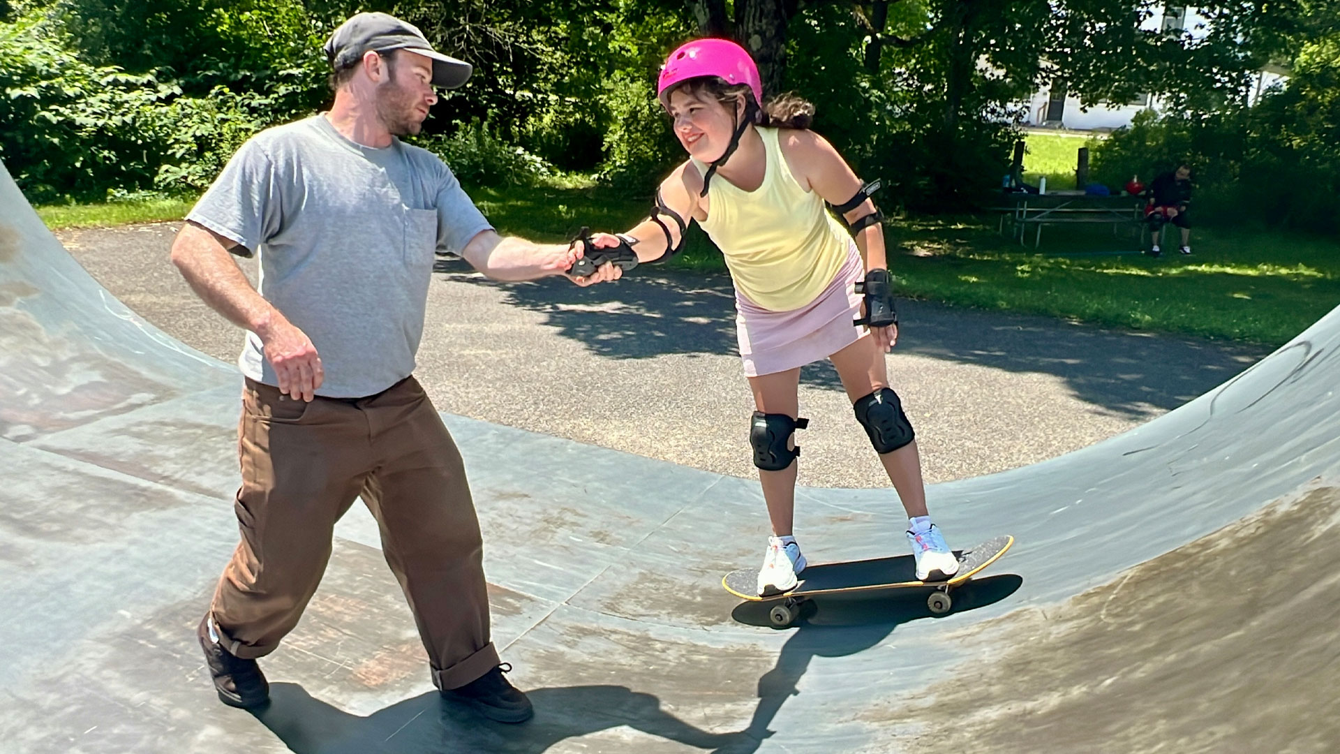 Girl on skateboard holding man's hand