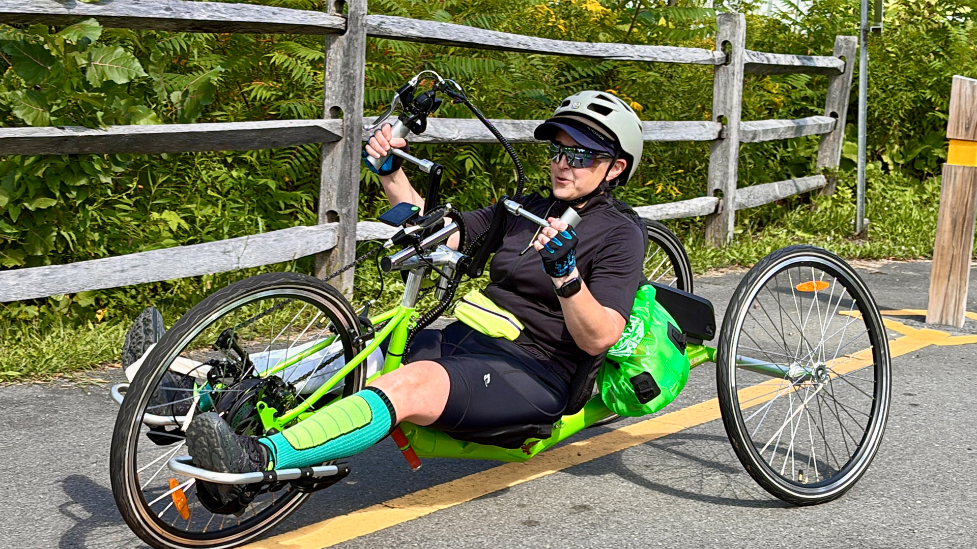 Woman riding a green recumbent hand-cycle bike