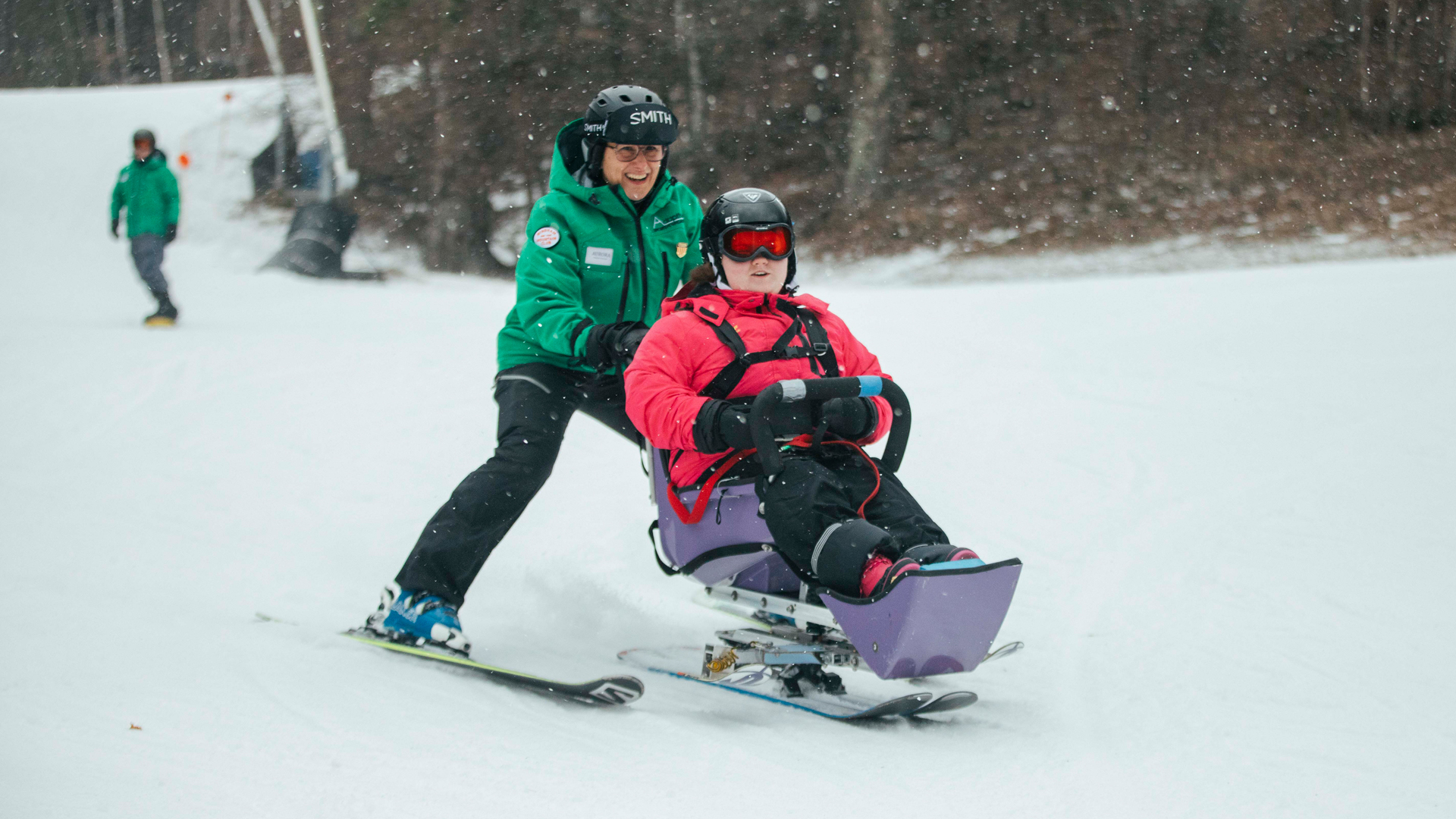 Woman in a bi-ski smiling with her instructor smiling behind her.